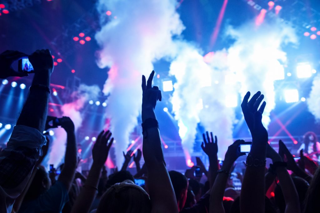 Pessoas com os braços levantados em um show Onde se hospedar no Rock in Rio