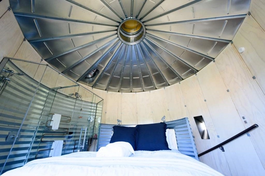 cama de casal com lençóis brancos e travesseiros em azul marinho
