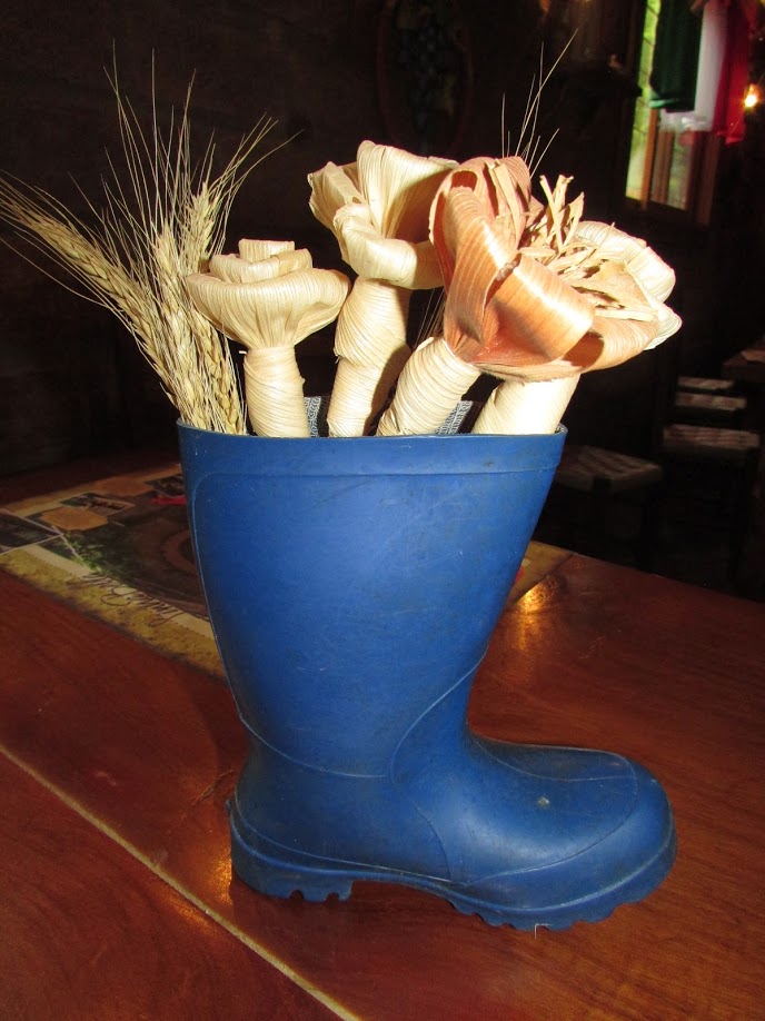 bota de borracha azul com itens decorativos em seu interior colocada sobre mesa de madeira