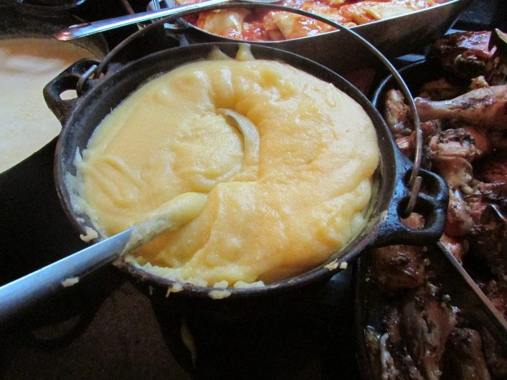 panela cheia com polenta com outros alimentos ao seu lado