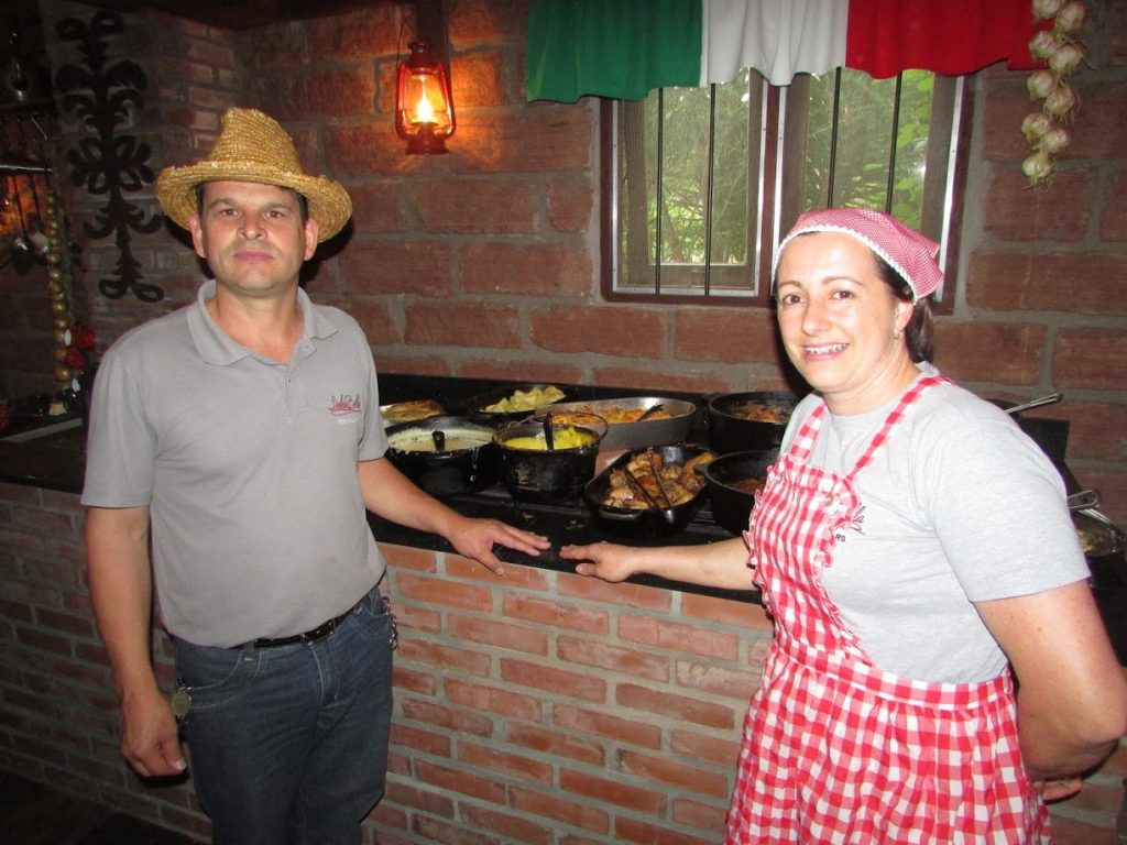 casal posa em frente a bufê de comida