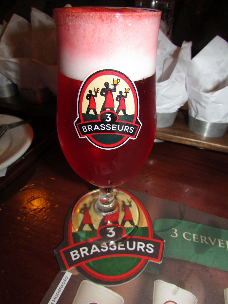 coquetel vermelho em copo identificado com o logo da 3 Brasseurs sobre mesa brewpub francês