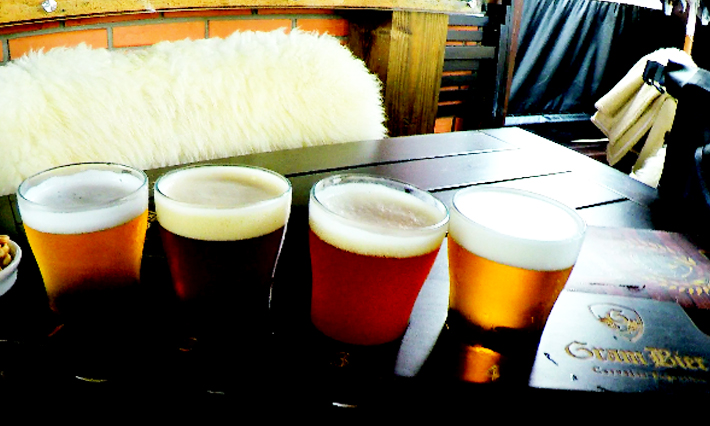 Mesa com vários copos de cerveja em diferentes cores e tonalidades Bus Bier Tour