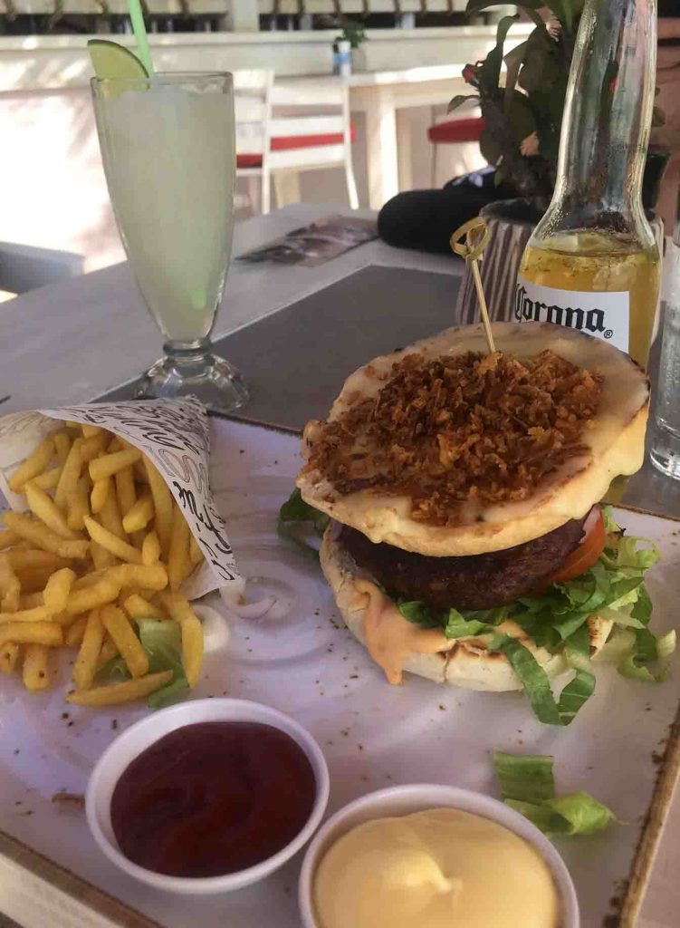 Hambúrguer com batata frita ao lado e molhos Onde comer em Curaçao