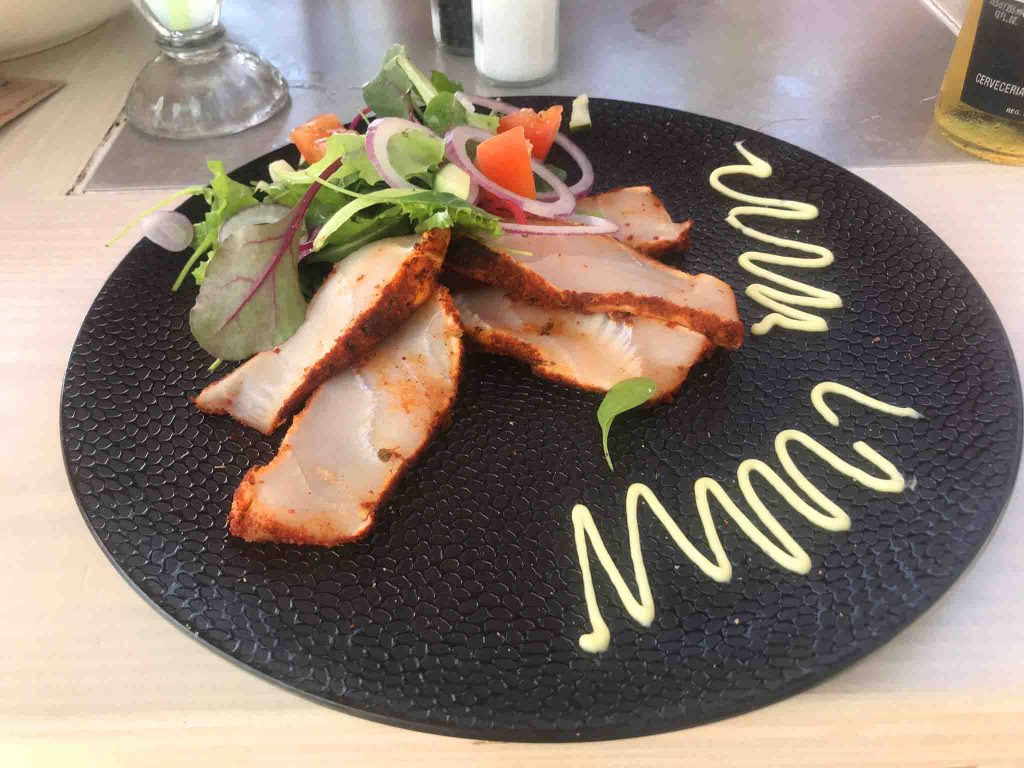 Comida sofisticada em prato preto com decoração Onde comer em Curaçao