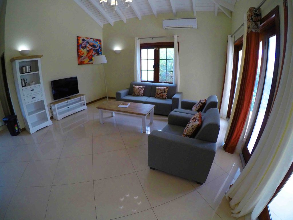 sala do apartamento com tv, sofa, cortina, sacada e mesa de centro Onde ficar em Curaçao