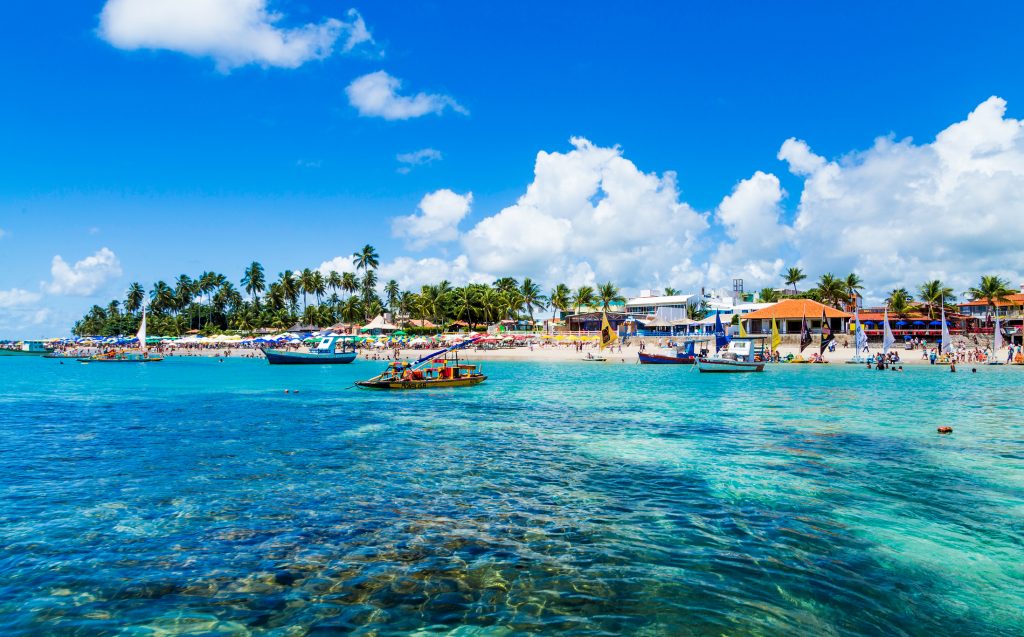 Praia de Porto de Galinhas com barcos, corais e tons azuis Praias no Nordeste