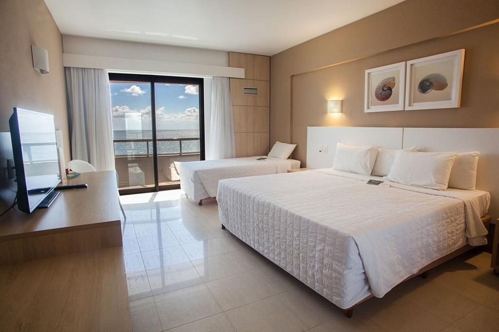 quarto de hotel com camas, sacada, mesa, tv Onde ficar em Balneário Camboriú