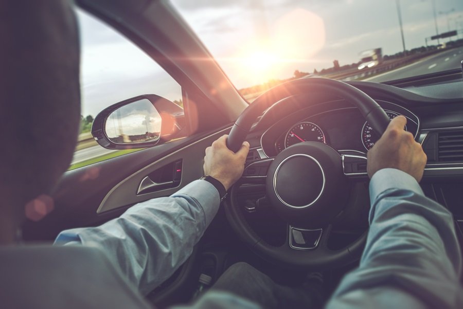 Homem segurando o volante do carro com as duas mãos enquanto dirige pela estrada Festival Cultura de Boteco