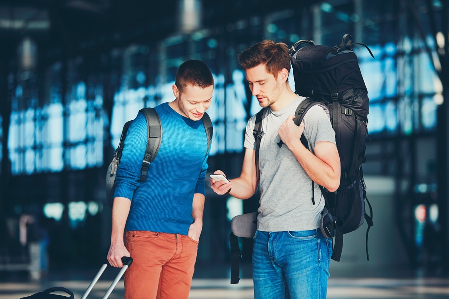 Dois homens indo viajar com mochilas e mala acionar o seguro viagem