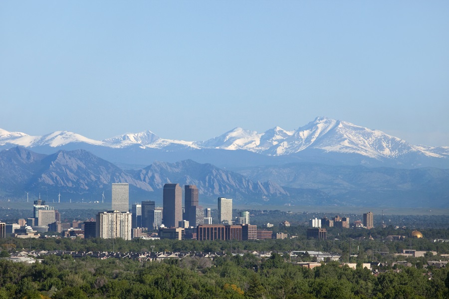 A neve cobriu o pico de Longs, parte das montanhas rochosas está alto no fundo com os arranha-céus do centro de Denver assim como hotéis, prédios de escritórios e prédios de apartamentos que enchem a skyline. La Casa de Papel