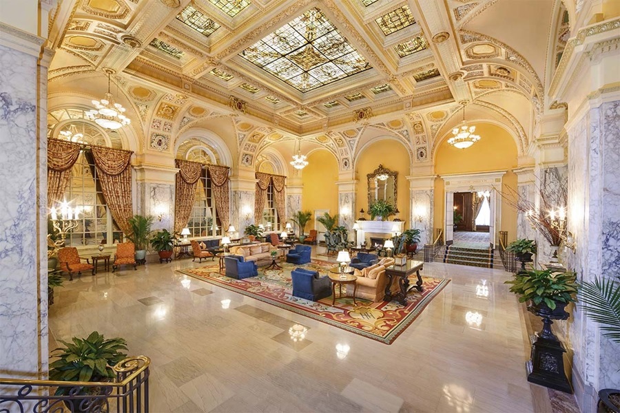 lobby de um hotel com plantas, cortinas, teto de vidro, tapete e cadeiras estofadas Sul dos Estados Unidos