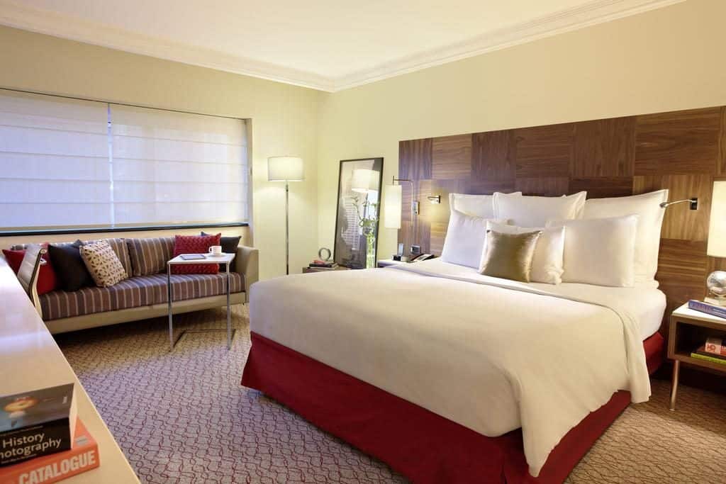Quarto com cama, abajur, sofá, mesa, criado mudo e detalhes em madeira Feriado da Independência