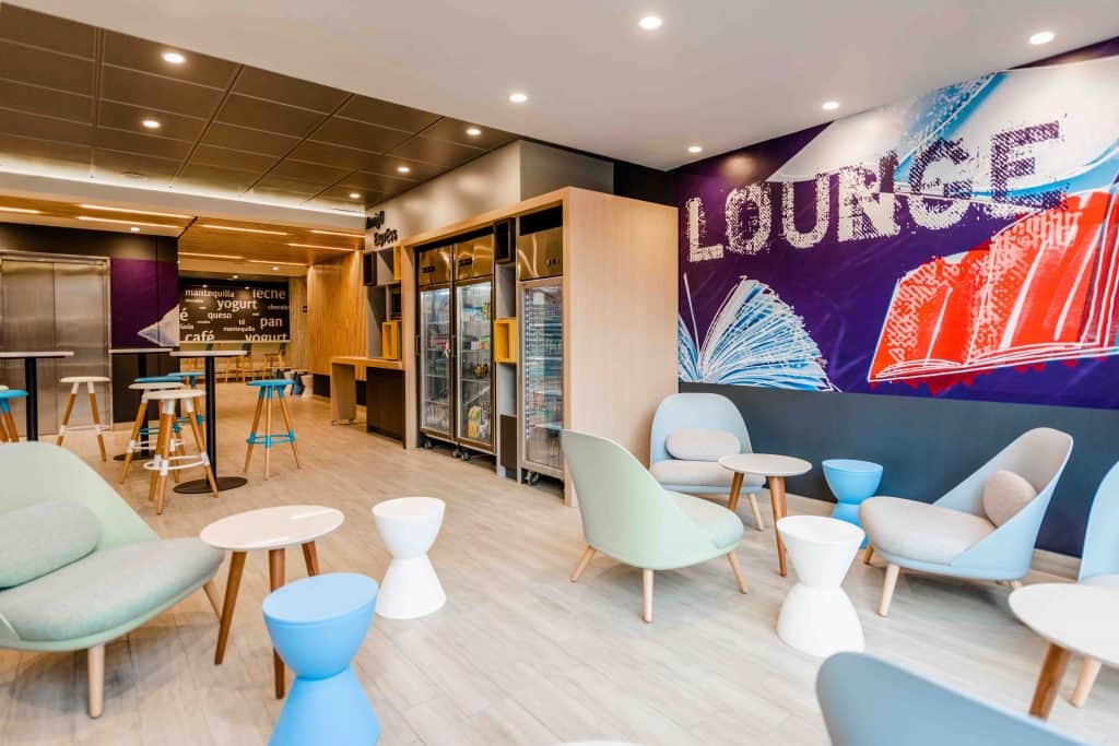 lounge do hotel com parede colorida, mesinhas, cadeiras e poltronas Ibis budget Providencia