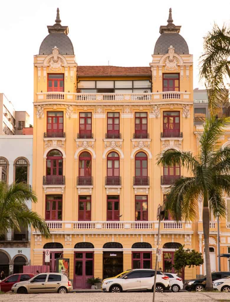 A fachada do hotel Selina Lapa Rio de Janeiro, amarela com janelas vermelhas