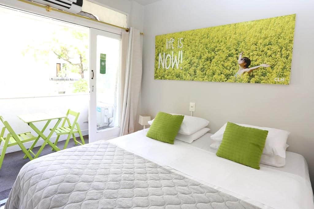 Quarto com decoração em verde e branco, com quadros, almofadas, cadeiras e mesa Onde se hospedar no Rock in Rio