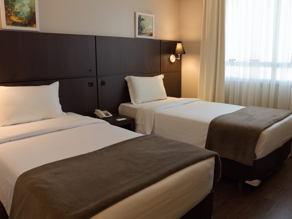 Um dos apartamentos do hotel como duas camas, cortina e quadros Bourbon Ponta Grossa
