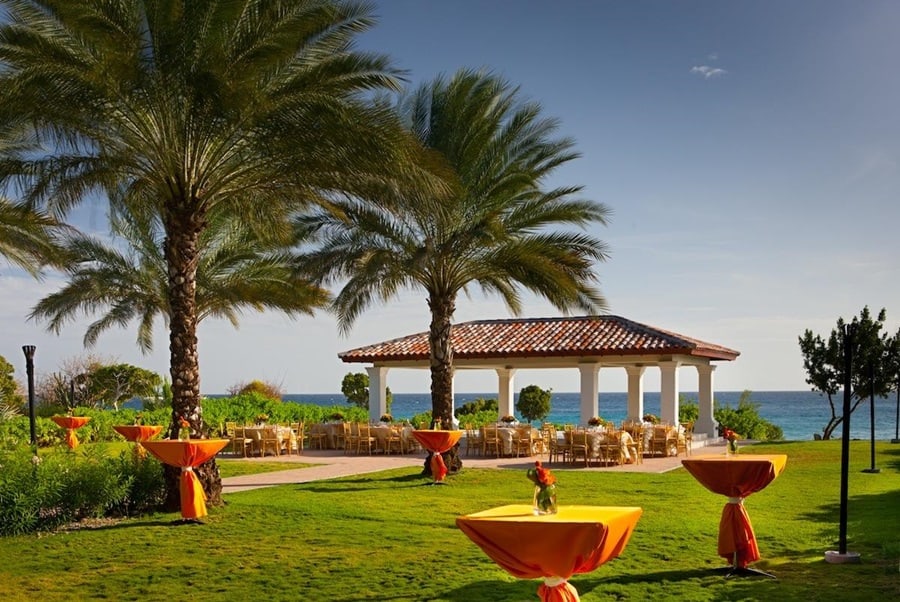 Jardim do resort com mesas laranjas, coqueiros e gramado Santa Barbara Beach & Golf Resort