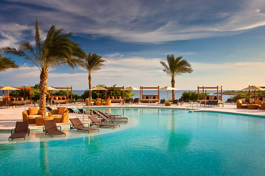 A piscina do resort com cadeiras espalhadas e coqueiros Santa Barbara Beach & Golf Resort