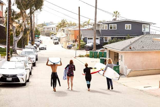 quatro pessoas com pranchas de surfe caminhando pela rua surfe na Califórnia
