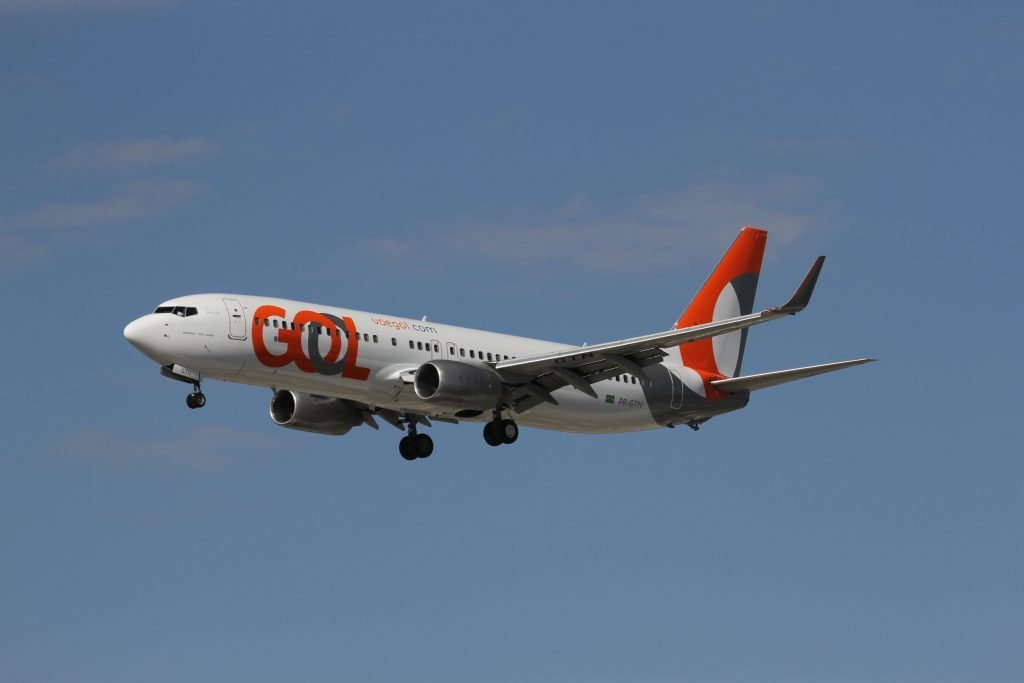 Aeronave da gol branca com detalhes em laranja voando Gol Foz do Iguaçu e Santiago