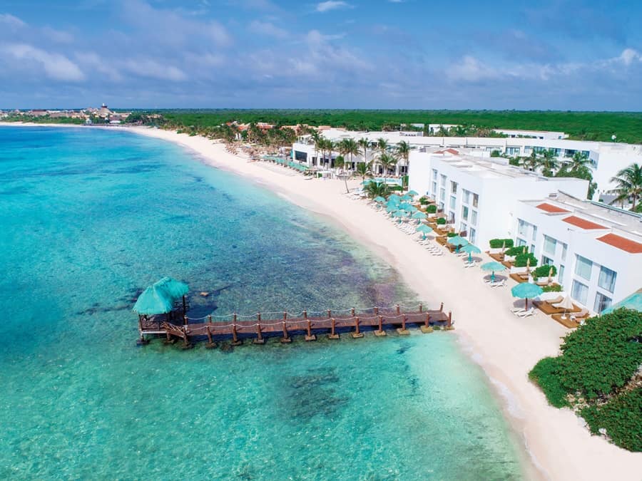 praia exclusiva com mar azul claro, cadeiras, mesas, árvores e hotel ao fundo Sunscape em Akumal