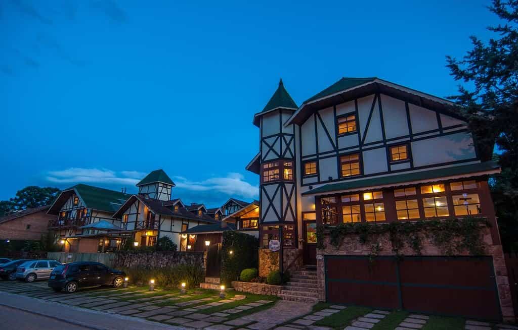 A fachada da Pousada Aguia Dourada com estrutura de madeira e decoração europeia O que fazer em Monte Verde