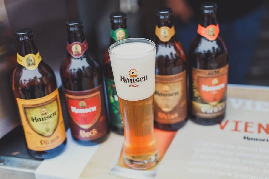 Mesa com garrafas de cervejas artesanais e um copo cheio de uma delas Festival de Cerveja Artesanal