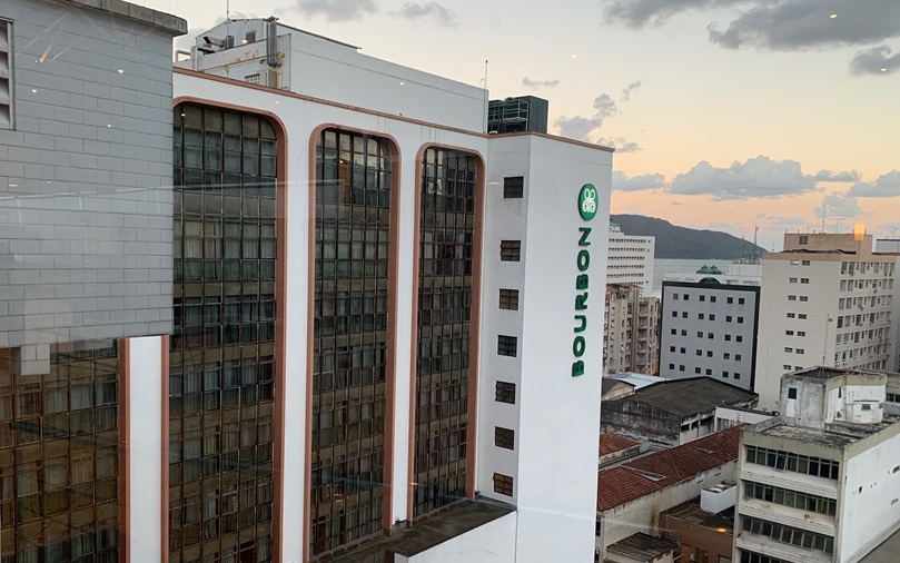prédio branco com janelas escuras refletindo outros prédios Bourbon Santos