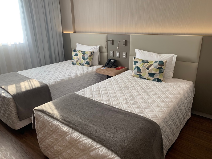 Quarto com duas camas de solteiro, cortina e decoração claras Rio Hotel by Bourbon Campinas