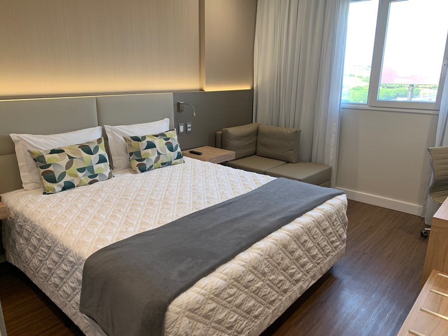 Quarto do hotel com cama de casal, poltronas, escrivania e janela Rio Hotel by Bourbon Campinas