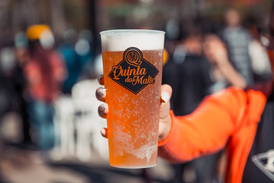 Mulher de roupa laranja segurando um copo de cerveja artesanal Festival de Cerveja Artesanal