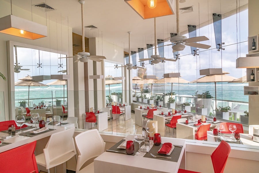 espaço do restaurante com decoração em vermelho, cadeiras, mesas, luzes e ventiladores de teto Sunscape em Akumal
