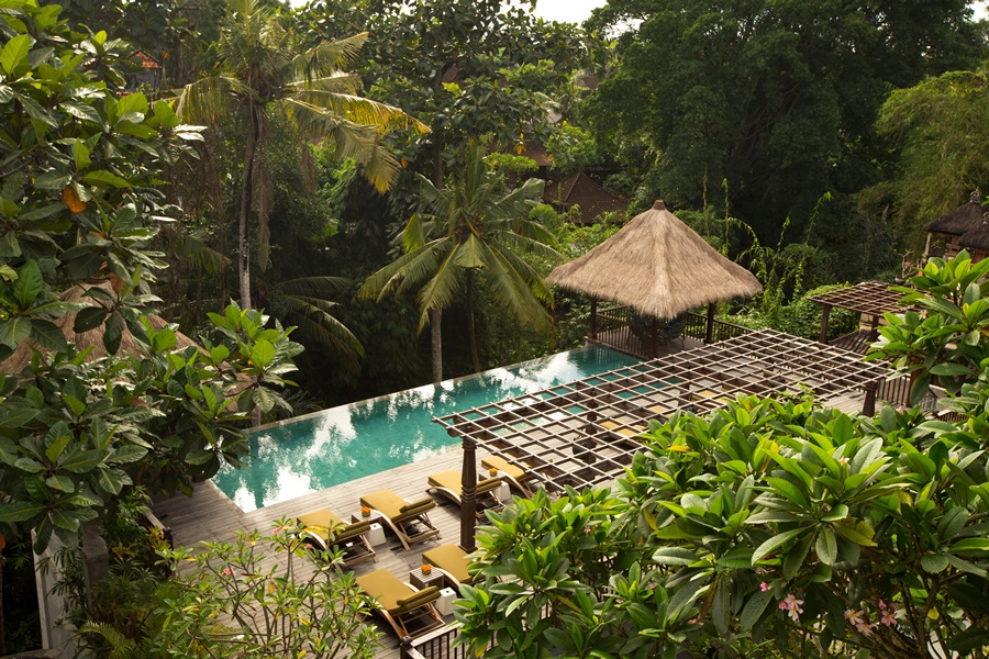 Espaço do resort com área verde, cadeiras, tenda e piscina azul destinos para se inspirar
