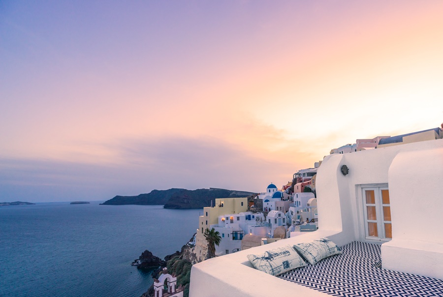 Por do sol em Santorini, com o céu roxo, e terraço de uma das acomodações destinos para se inspirar