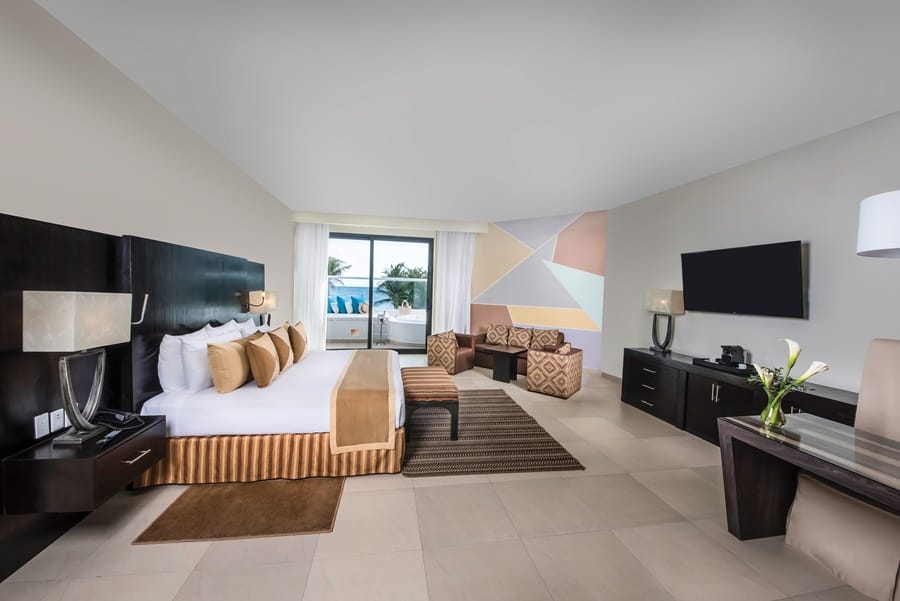 quarto com cama, abajur, tapete, cadeira e estofados, televisão e mesa Sunscape em Akumal