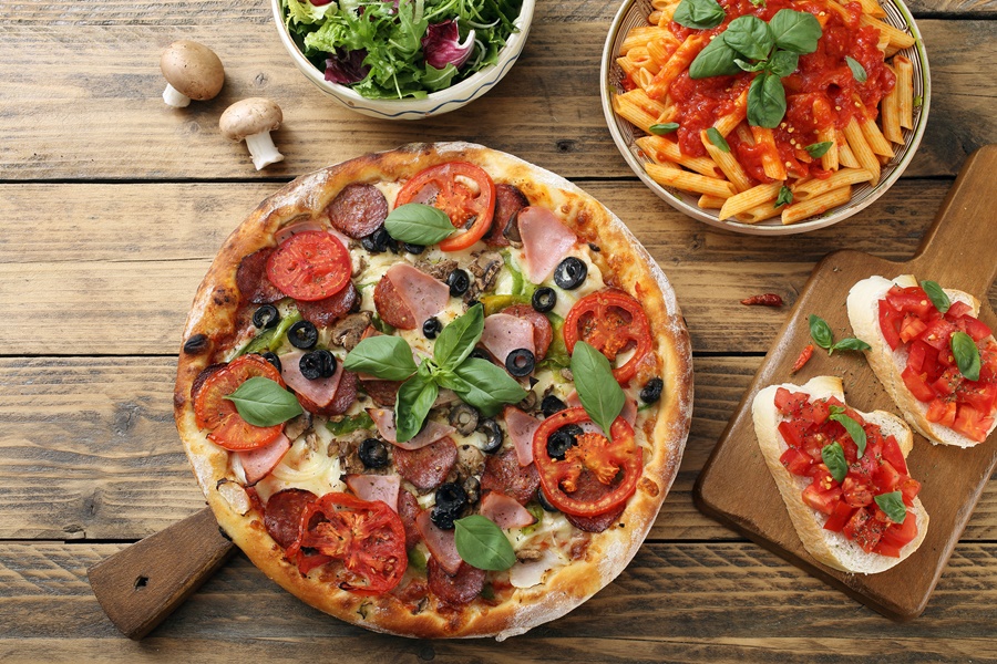 Mesa com pratos italianos como pizza, massa, brusqueta e salada Bourbon Cambará Hotel