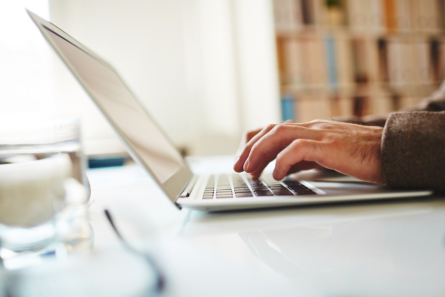 Pessoa digitando no laptop branco que está em cima de uma mesa Passagens aéreas mais baratas