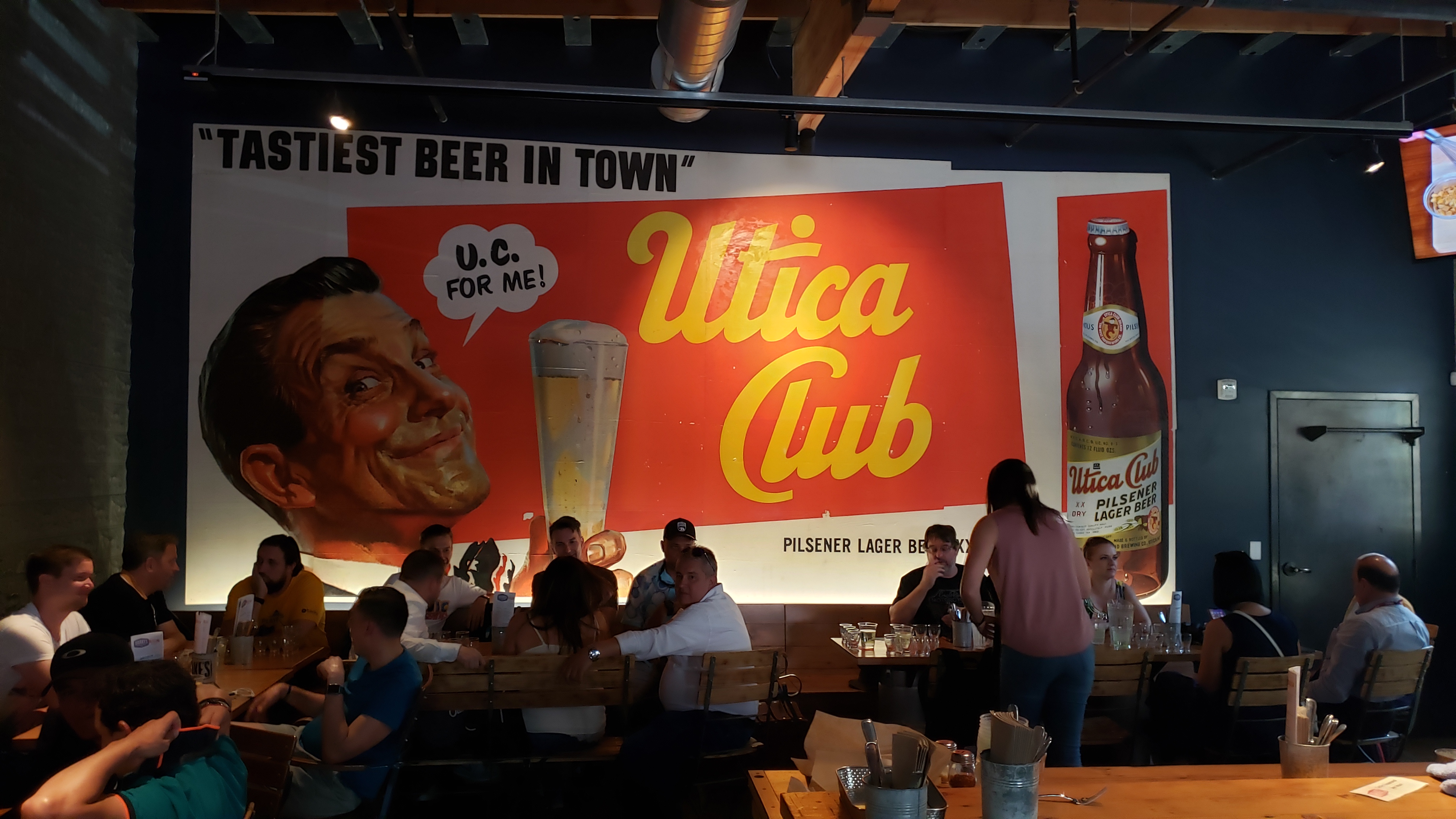 letreiro tipo retro com homem e pessoas sentadas Cervejaria