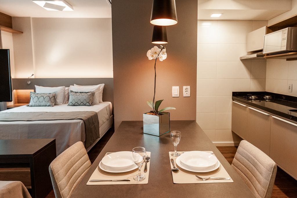 Quarto de hotel com cama, mesa, cadeiras, e cozinha anexa Quality Porto Alegre