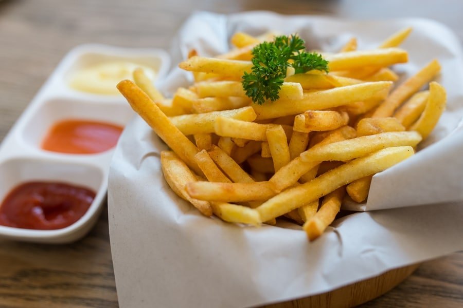 Batata frita sobre mesa acompanhada de molhos festival da batata