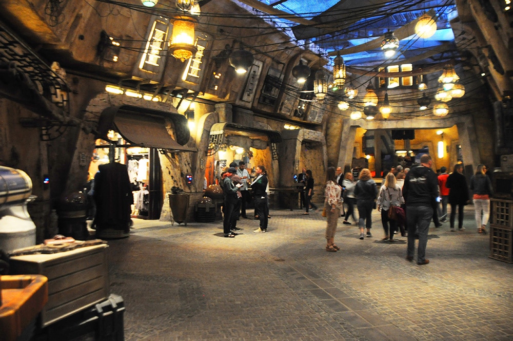 Ambiente com pessoas e andoides nos cantos Star Wars Galaxy's Edge; saiba como visitar