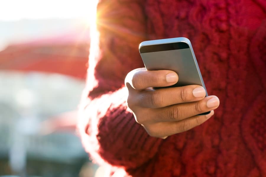 pessoa de casaco vermelho segurando um celular na mão como usar celular no exterior