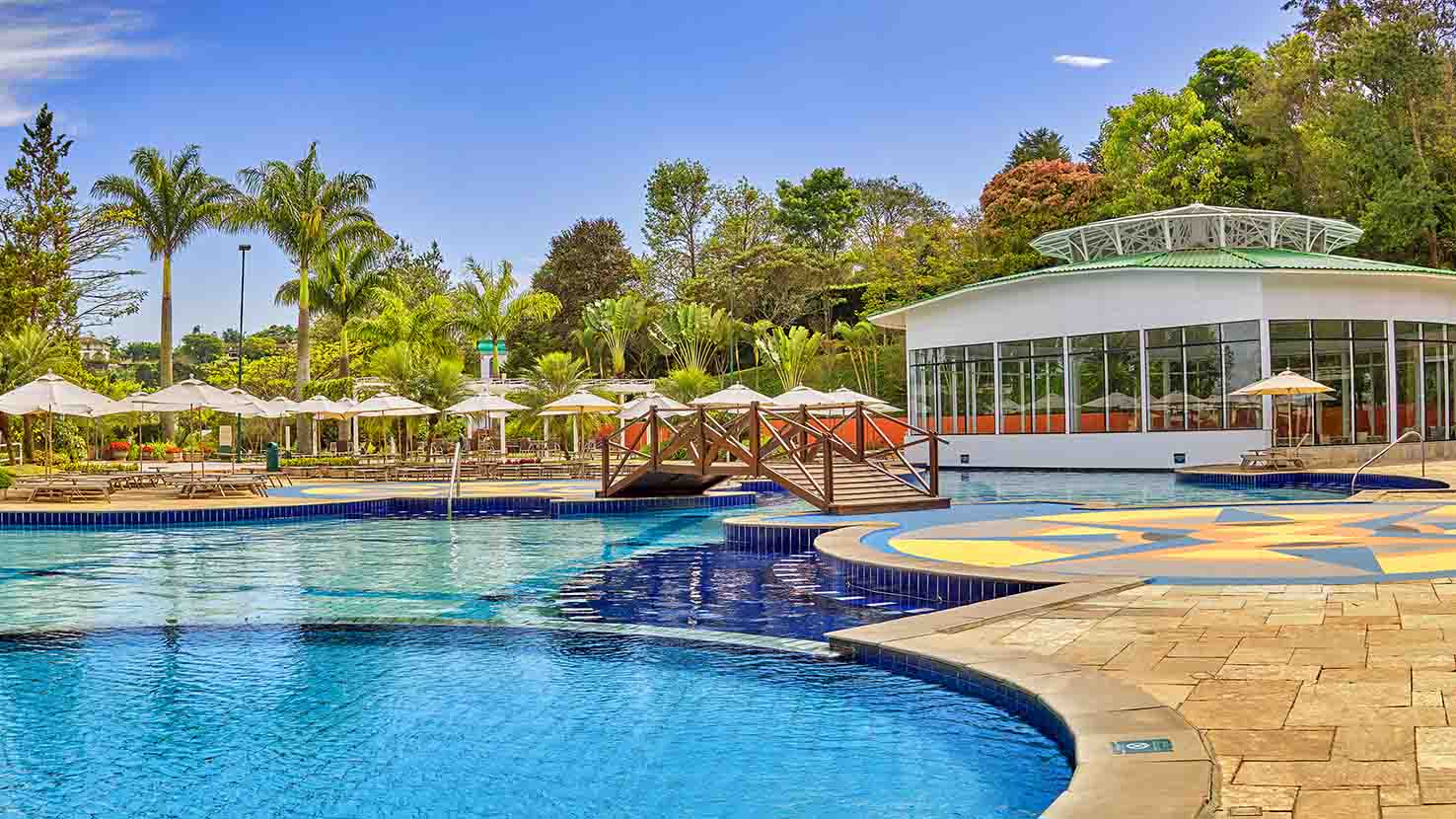 Piscina com cadeiras e guarda sol de fundo Piscina do Bourbon Atibaia