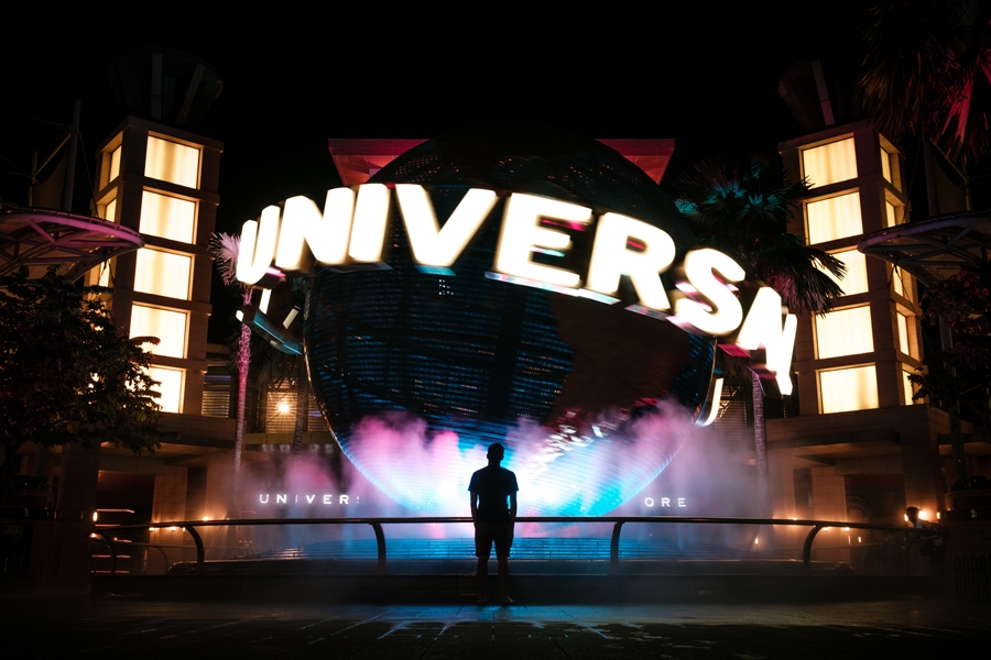 homem parado em frente ao globo do universal studios universal studios
