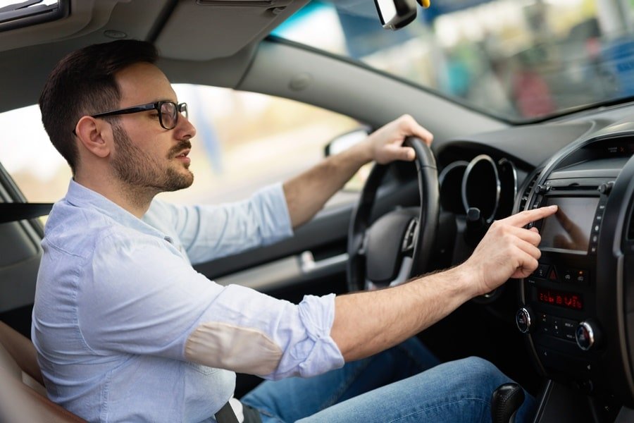Homem de camisa branca dirigindo um carro Como alugar um carro na Rentcars