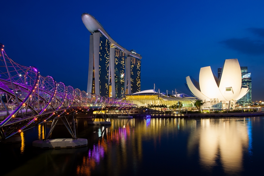 area da marina bay em singapura a noite com helix bridge em primeiro plano marina bay