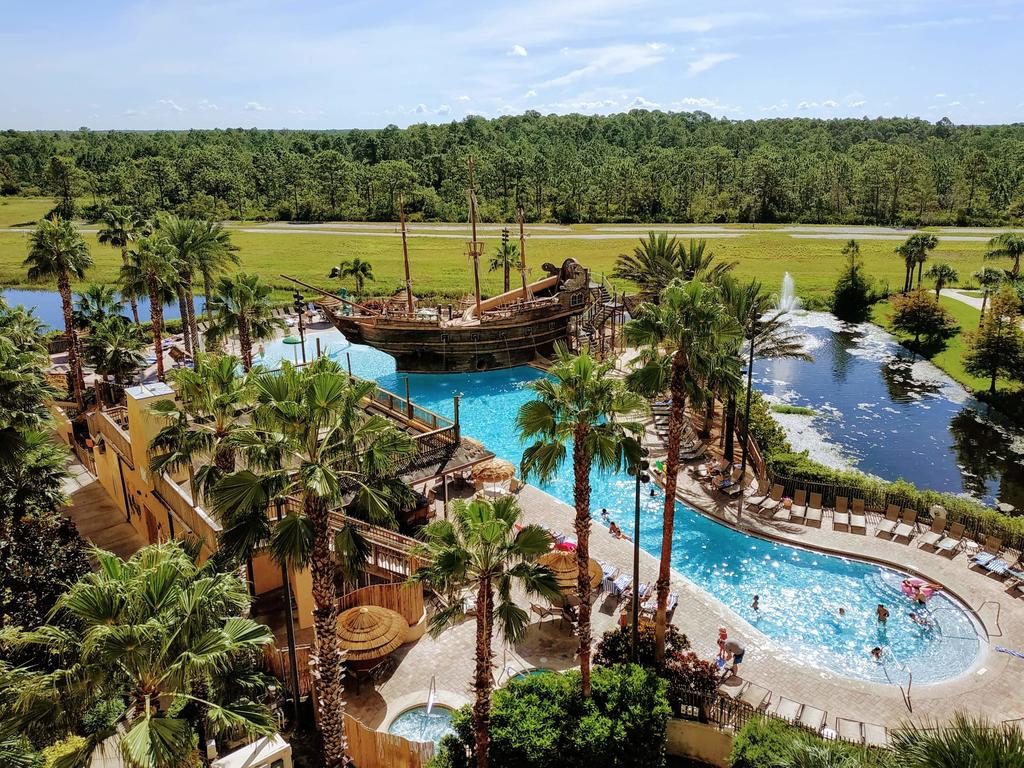 Vista do alto do Lake Buena Vista Resort Village com piscina, barco pirata e área verde Hotéis para férias no exterior