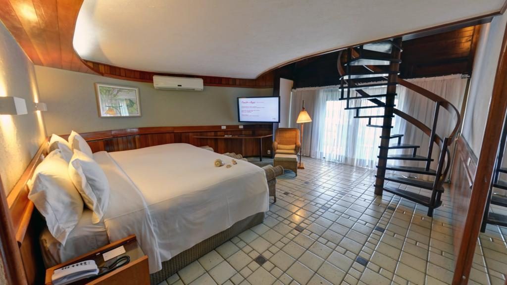 Um dos quartos do Summerville Beach Resort com cama, tv, escada