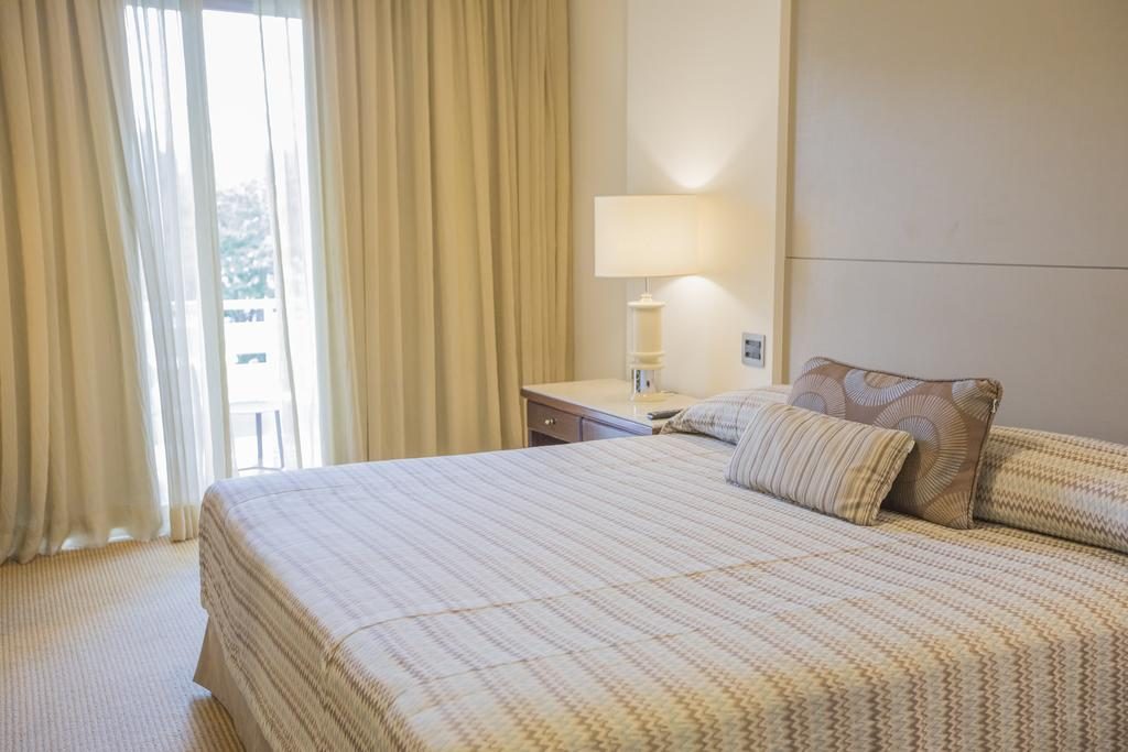 Quarto de hotel com cama, cortina, sacada e abajur Hotéis e resorts para férias